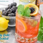 The Lily Oaks drink is a combination of cranberry juice, orange liqueur, lemonade, and vodka combined and garnished with mint, lemon, and blackberries.