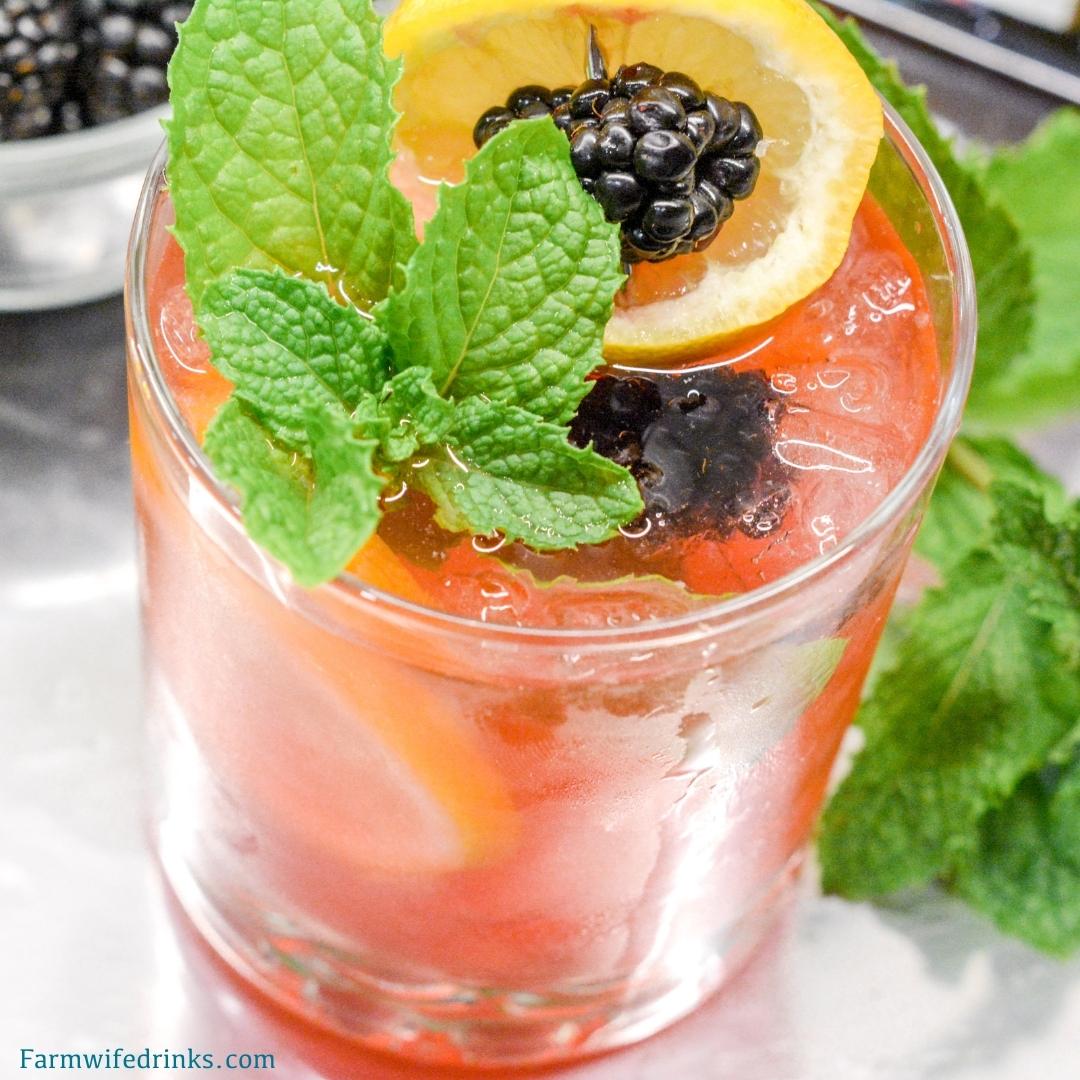 The Lily Oaks drink is a combination of cranberry juice, orange liqueur, lemonade, and vodka combined and garnished with mint, lemon, and blackberries.