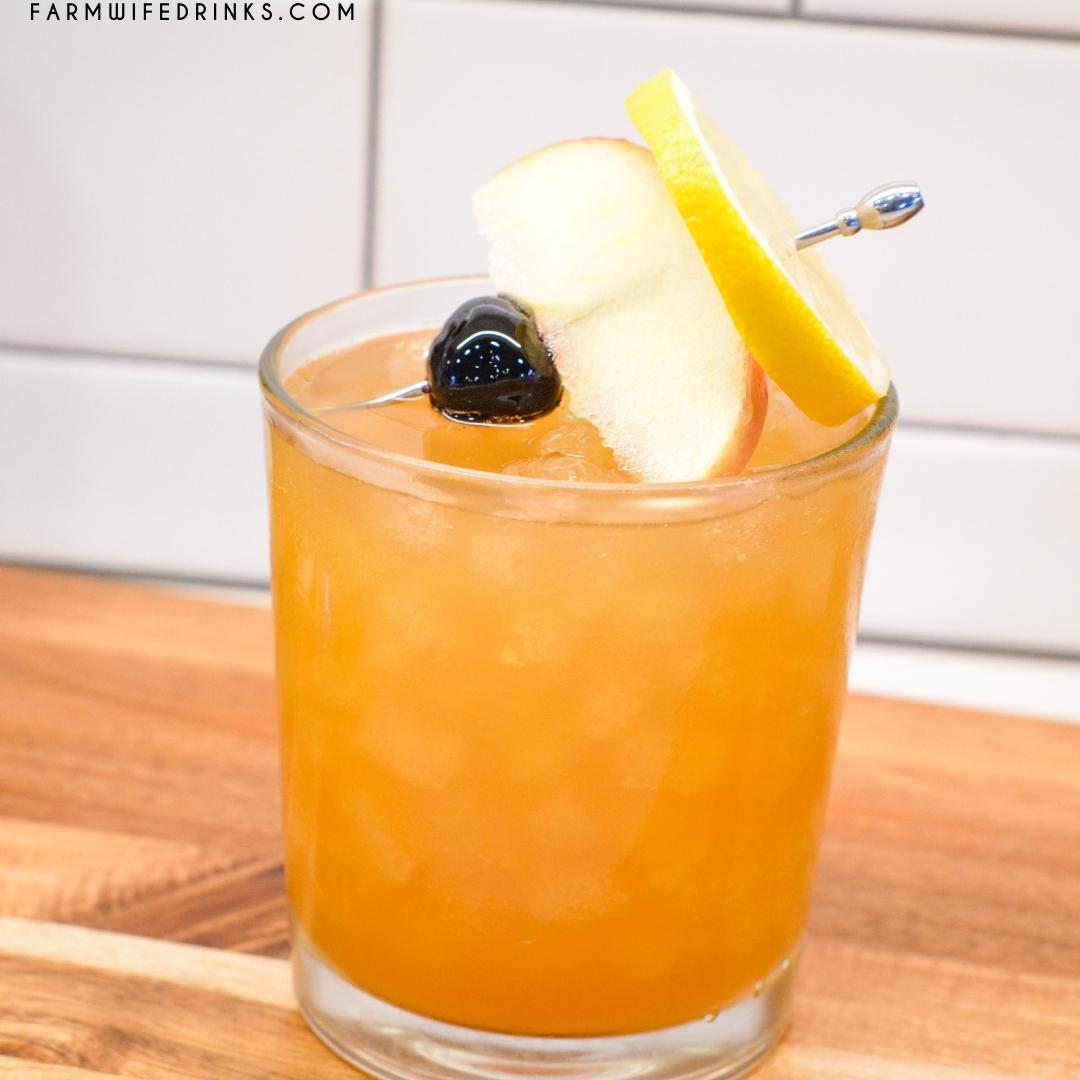 Garnish the apple cider amaretto sour with maraschino cherries, apple slices, and lemon slices.