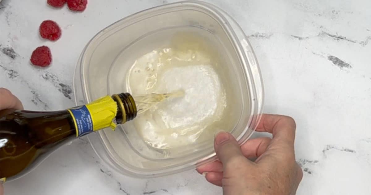 Pour small bottle of Champagne into plastic container to set into freezer.