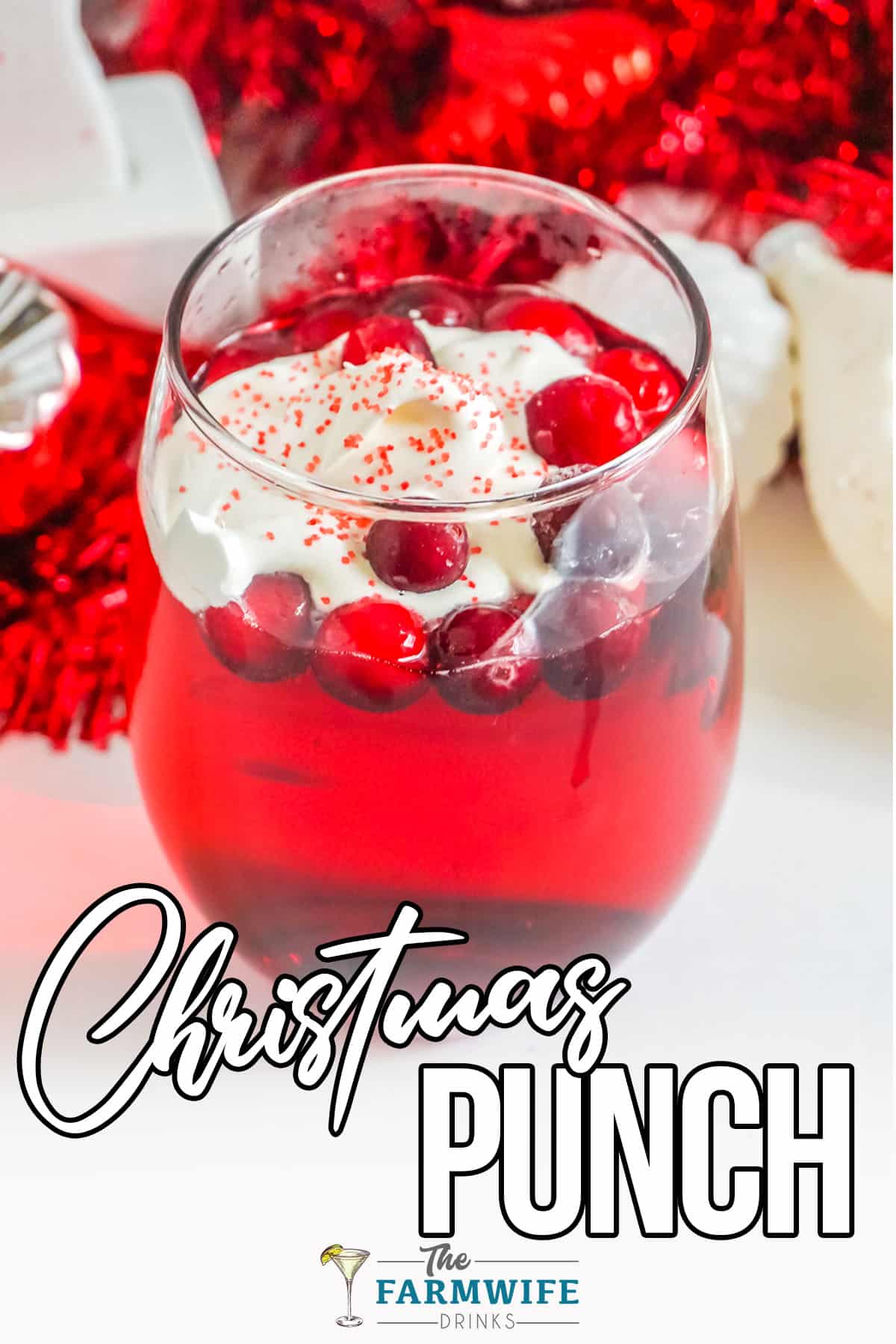 Red glass of Christmas Punch topped with Cranberries and sprinkles.