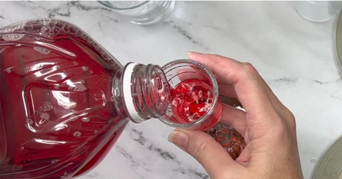 Measuring out Cranberry Juice Cocktail for Cranberry Margarita.