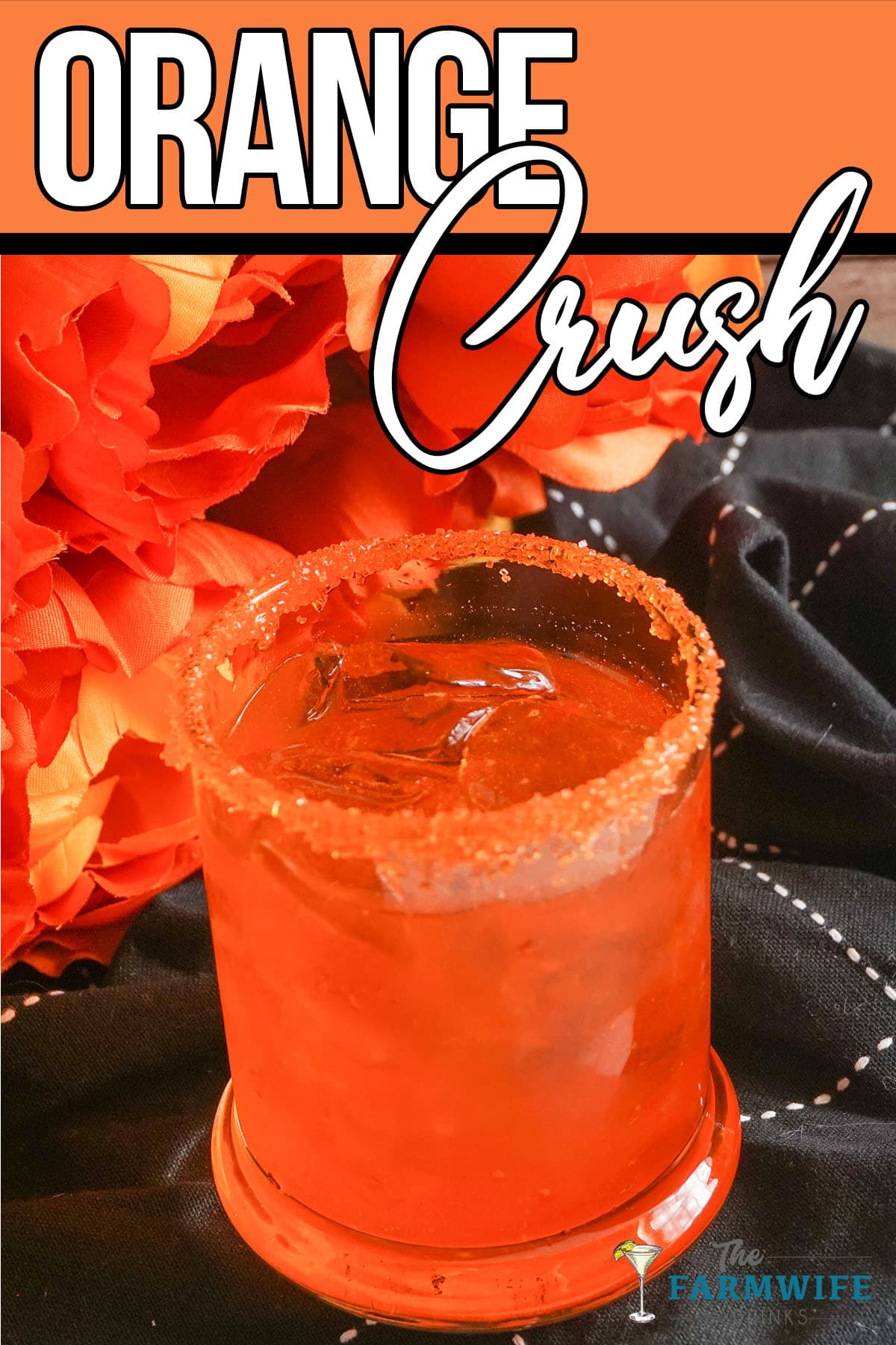 Orange flowers behind an sugar rimmed Orange Crush Cocktail drink.