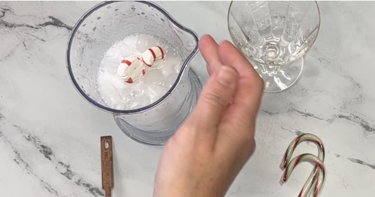 Adding in peppermint into the immersion blender container.
