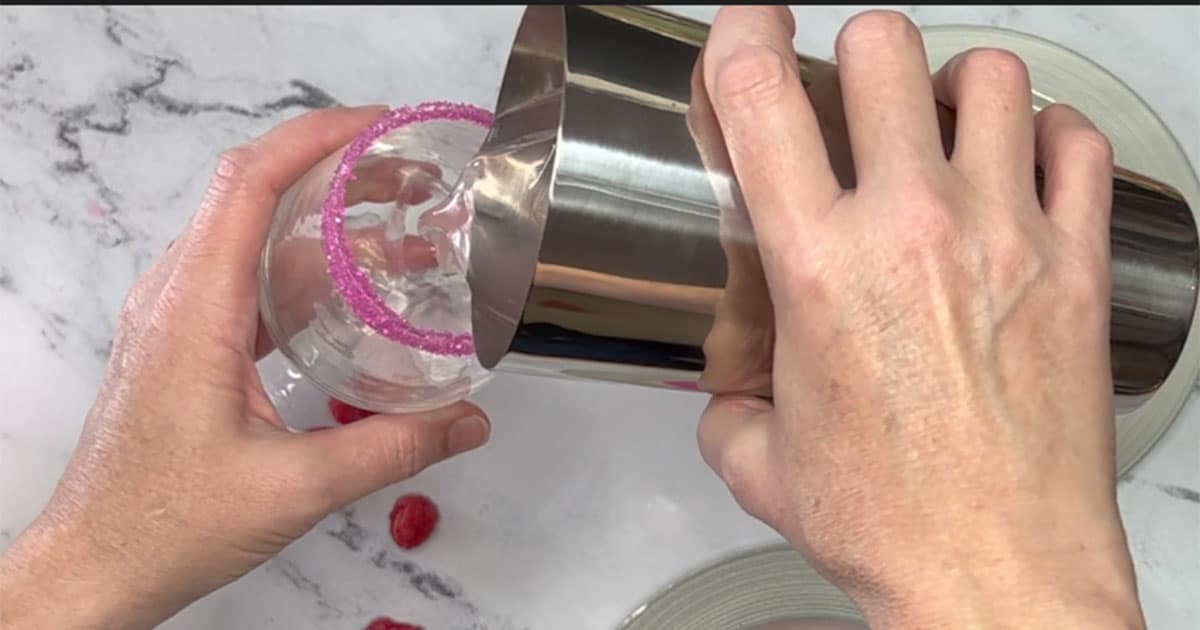 Pouring Shaken Raspberry 7up Punch into sugar rimmed glass.