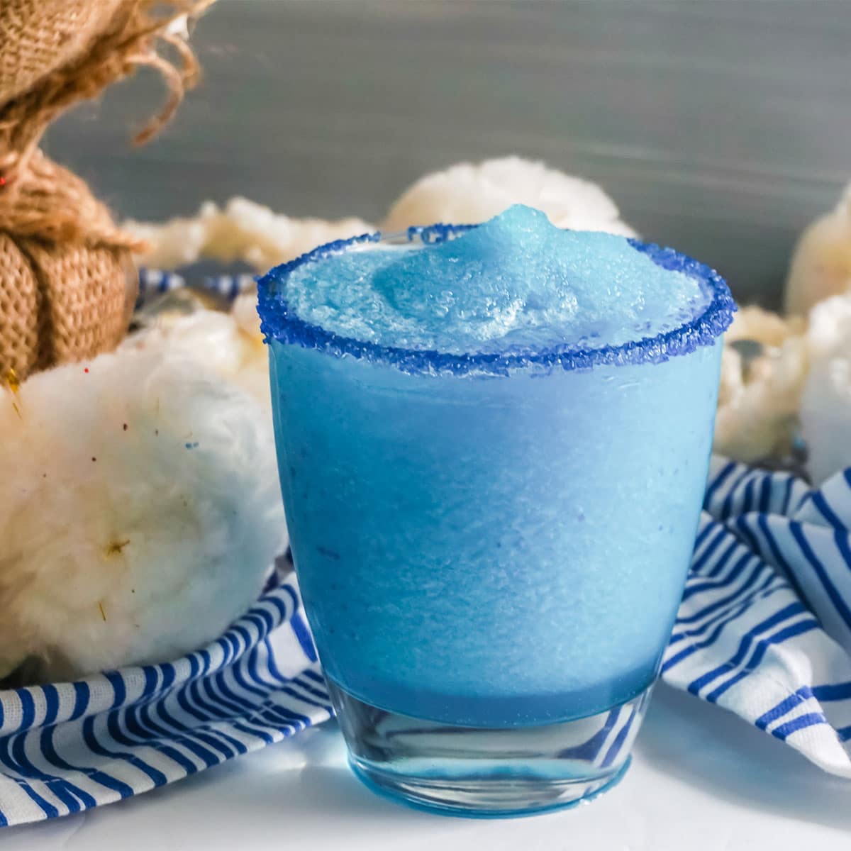White fluffy cotton behind Snowball Punch with blue sugared rim.