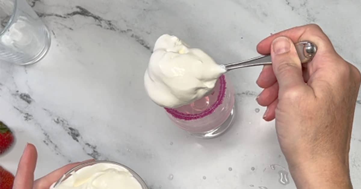 Adding in Whipped topping to Decorated Strawberry Shortcake Cocktail.
