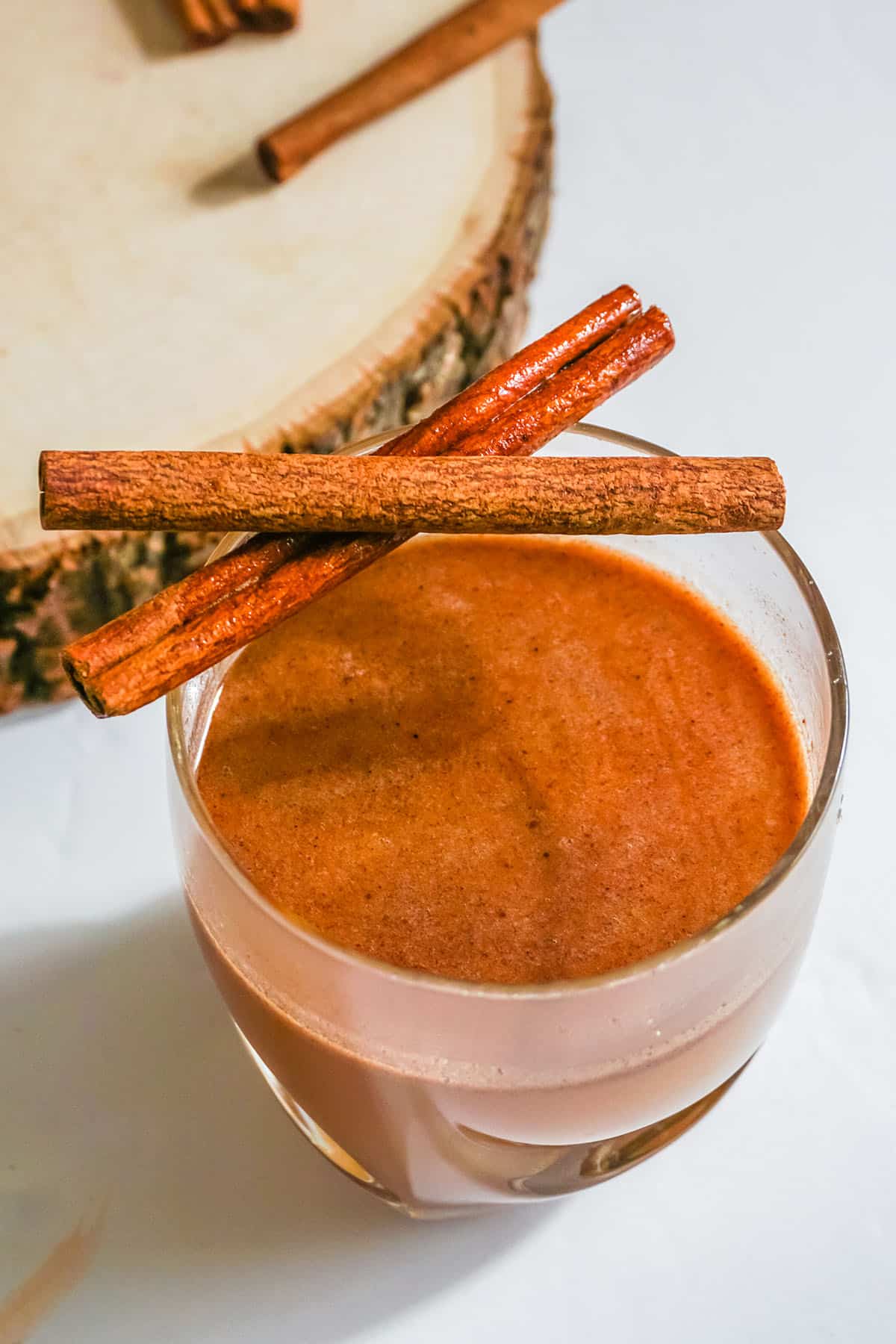 Wood tray next to Hot Buttered Bourbon and cinnamon sticks.