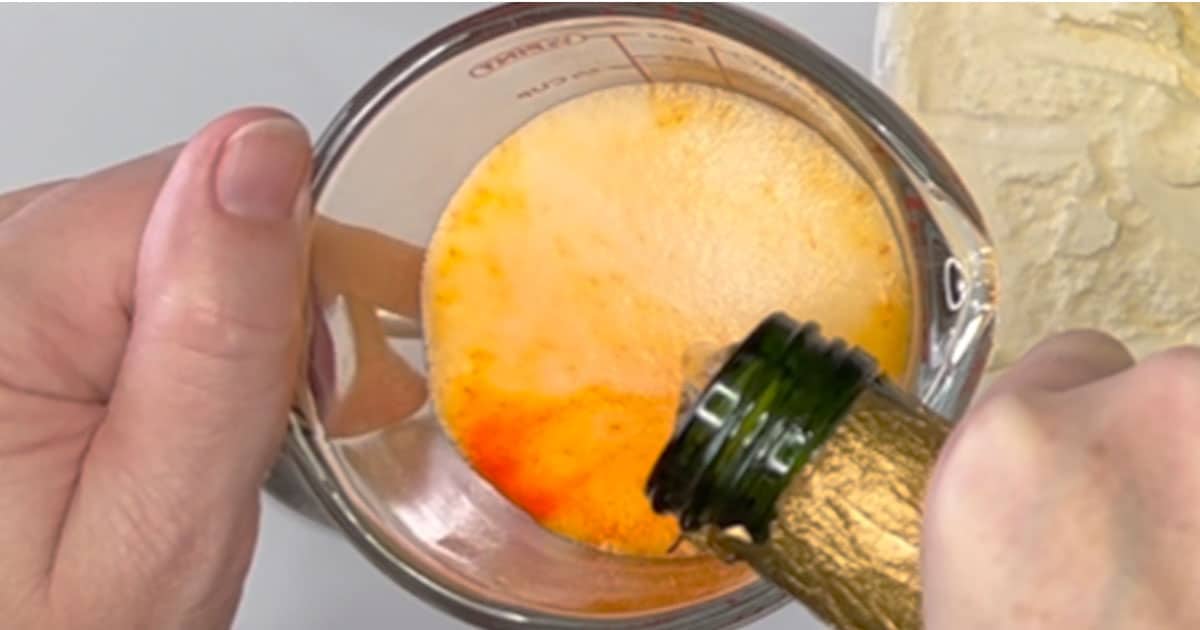 pouring in champagne into crush drink mix for Creamsicle Mimosa Float.