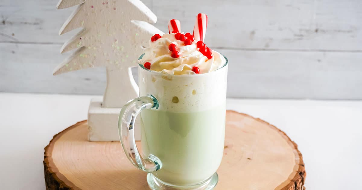Grinch Hot Cocoa with white tree behind it.