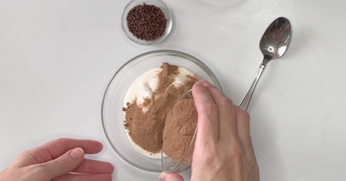 Sprinkling Hot Cocoa mix over whipped topping to create Whipped Hot Cocoa.