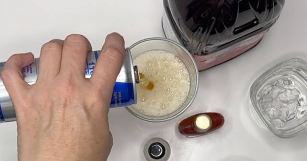 red bull being poured into a glass to make a Vegas Bomb Cocktail